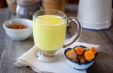 Golden milk. Turmeric herbal medicine, an anti-inflammatory. Shallow DOF, focus on the brim of the glass and the foam on milk